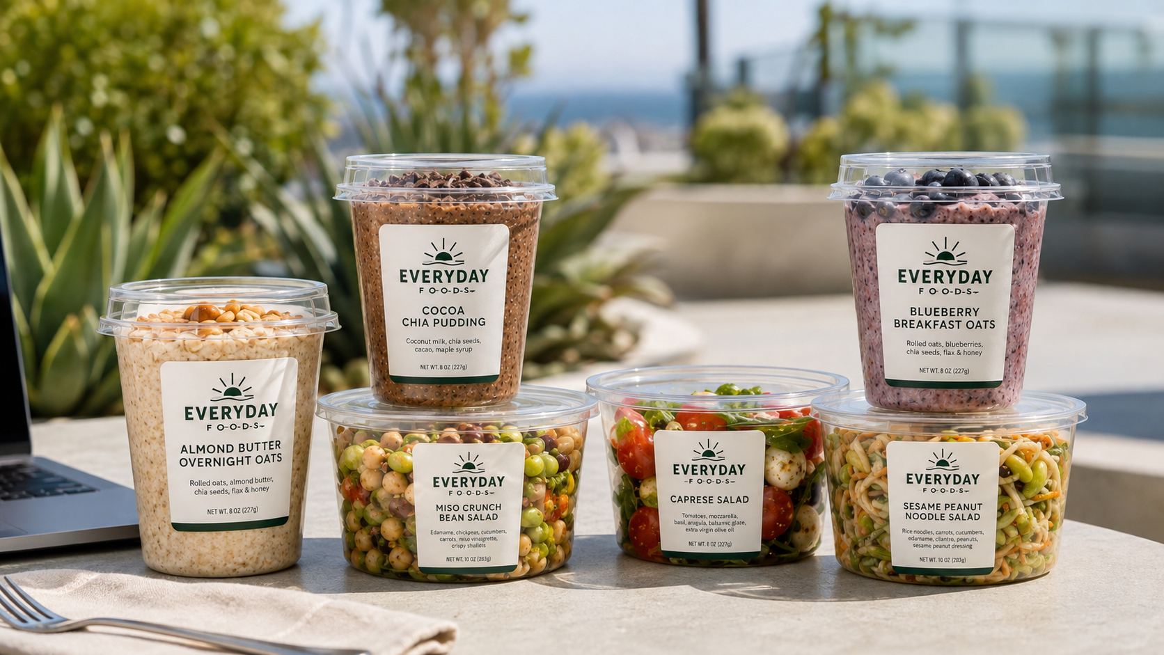 Everyday Foods cups and salads on a sunny outdoor terrace table
